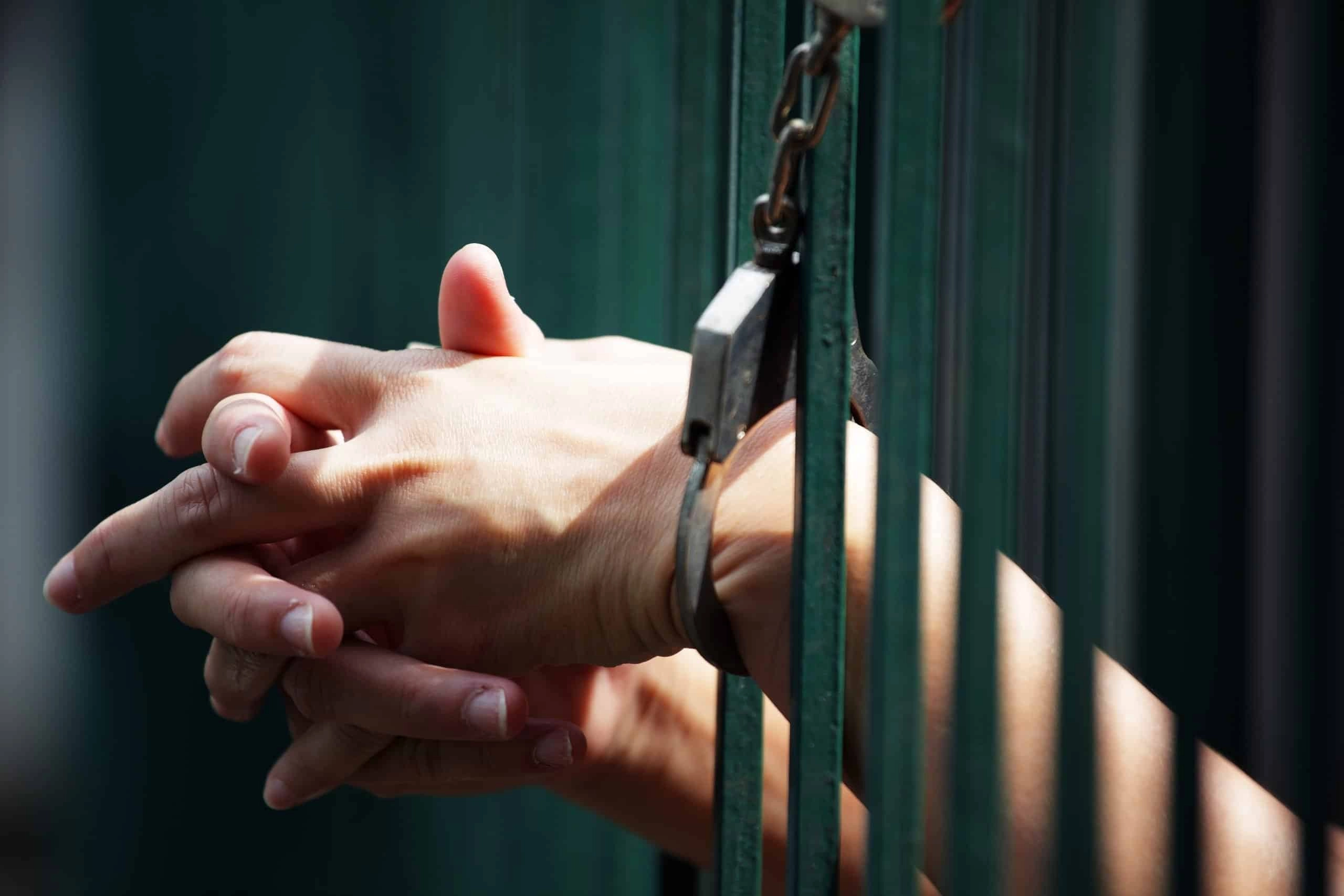 hand of prisoner in jail background.