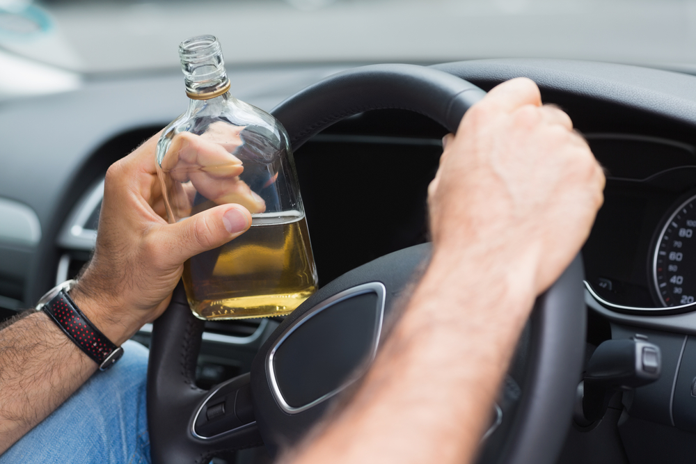 Photo of a Man Drinking Alcohol While Driving His Car